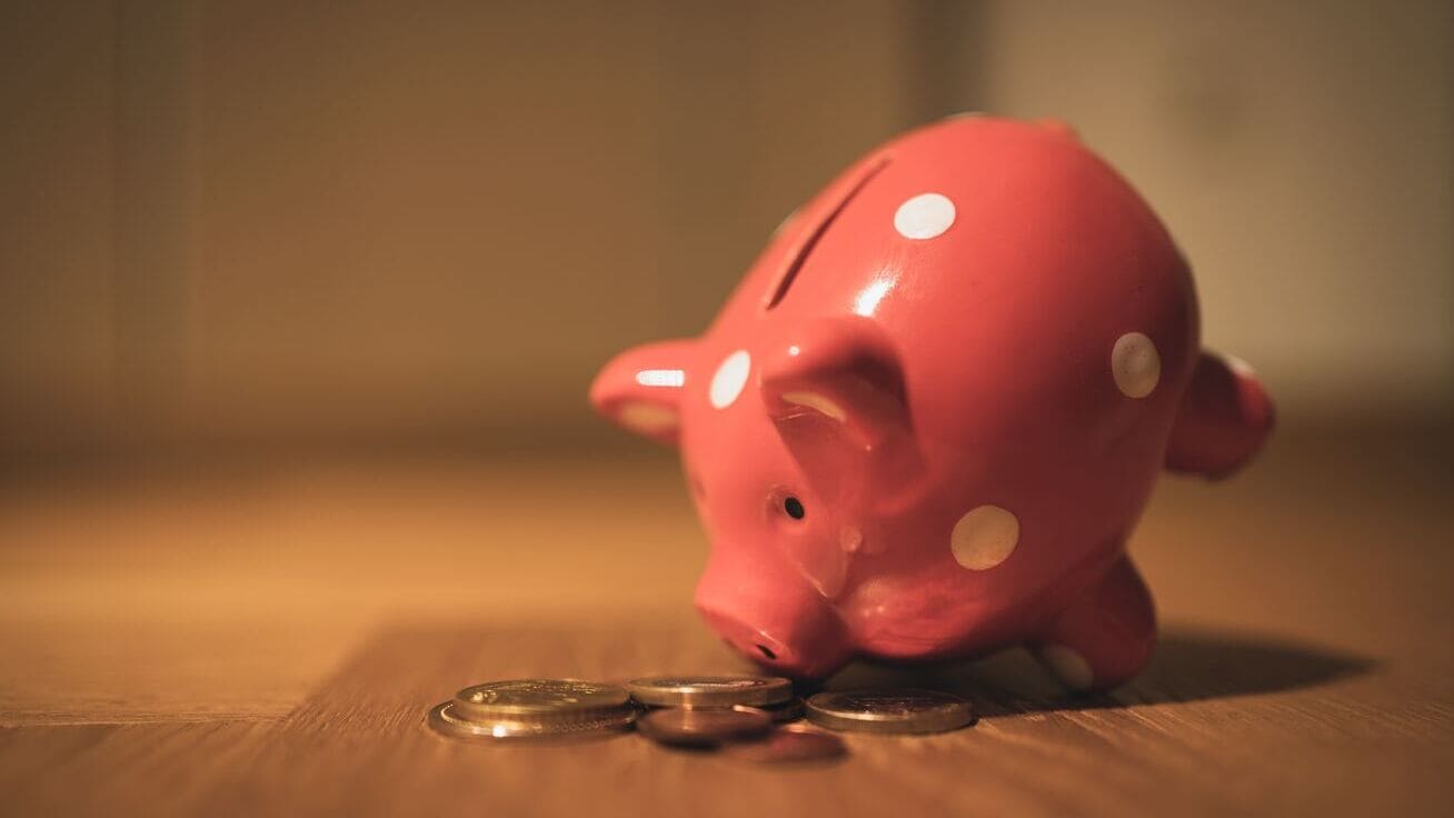 Rosa Sparschwein mit Münzen auf einem Tisch