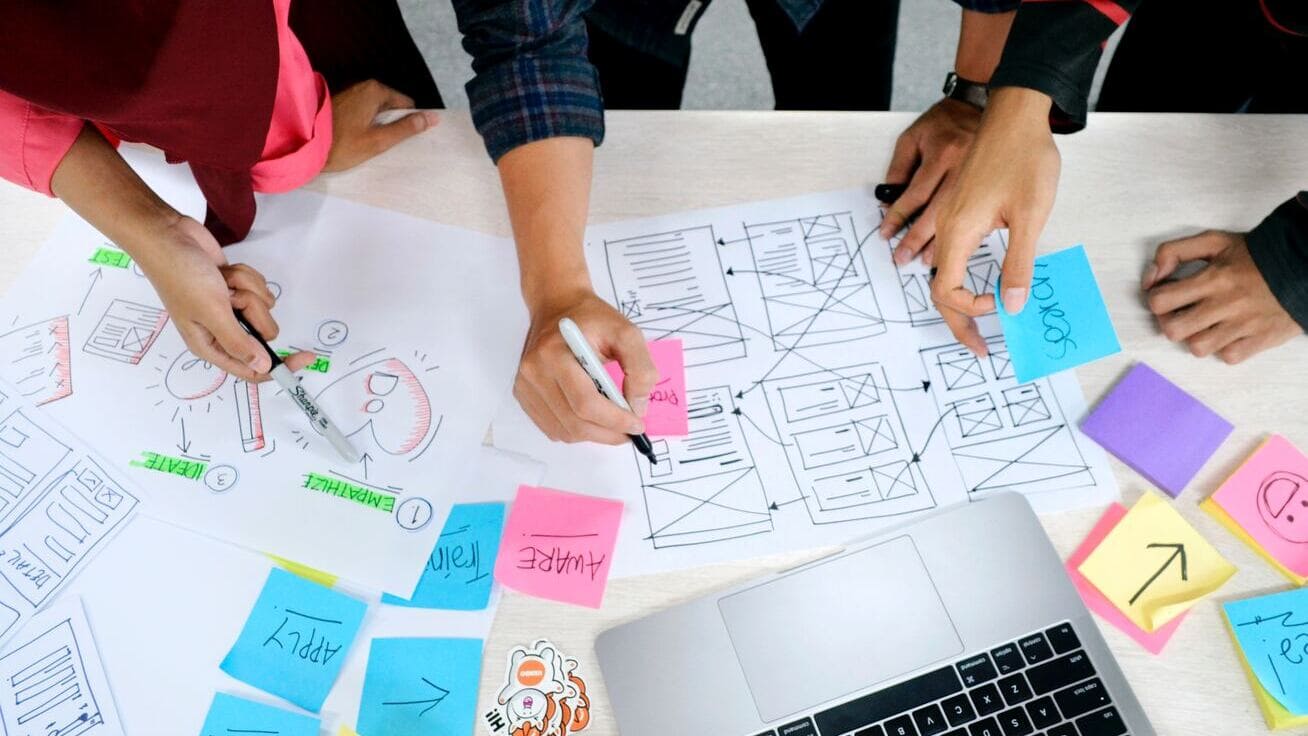 Team beim Brainstorming mit Haftnotizen und Skizzen auf einem Schreibtisch